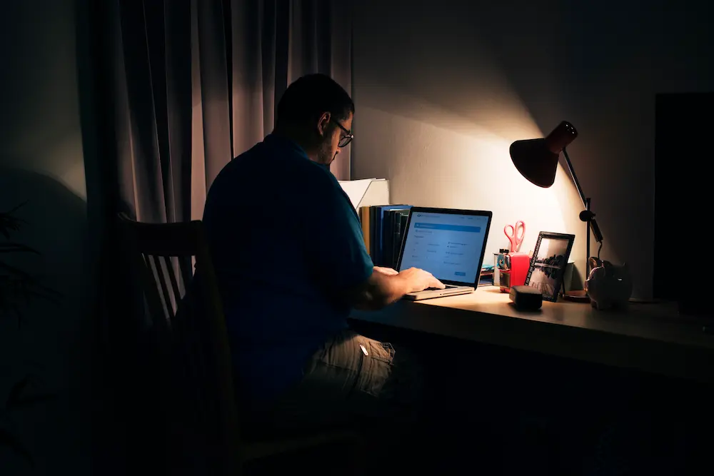 Persona usando una laptop de noche como representación de la relación cercana que algunas personas desarrollan con asistentes de inteligencia artificial.
